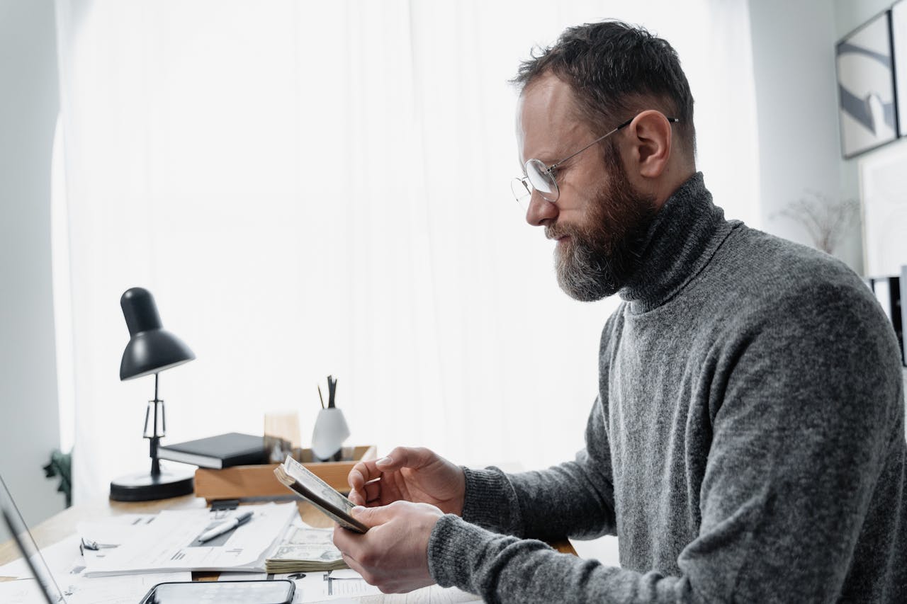 Adult male reviewing documents at a desk with a modern setup, conveying focus and concentration.